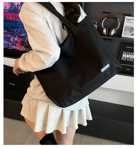 Detail view of large black nylon tote bag with MSDTON label in a minimalist setting