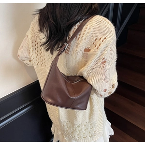 Sac à bandoulière en cuir marron avec sangle réglable porté par un mannequin en intérieur