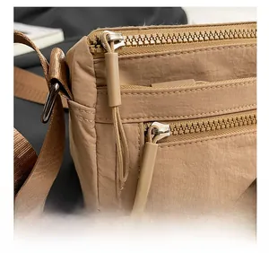 Close-up of khaki nylon shoulder bag showing smooth zippers and durable fabric texture