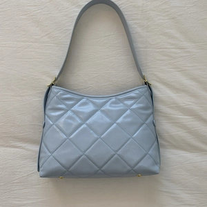 Détail du sac à main bleu clair en cuir matelassé avec pieds et boucles dorés