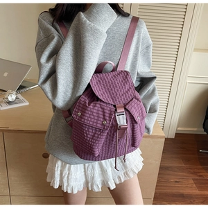 Detail view of purple checkered backpack with drawstring closure and buckle on a model