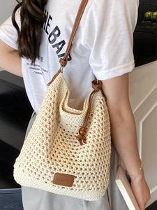 Minimalist cream woven crochet tote bag with brown leather straps and wooden bead detail