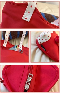 Detail view of strawberry tote showing polka dot handle, zipper and brand tag