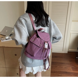 Detailed side view of purple plaid backpack featuring flap closure and buckle straps