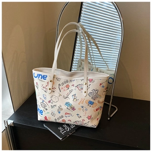 Detail shot of white canvas tote bag featuring colorful graffiti prints and rivets