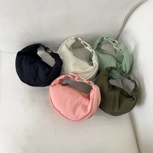 Five lightweight nylon crescent bags in various colors displayed on a white sofa
