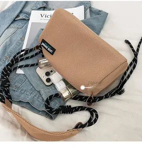 Detail of a brown mesh crossbody bag with a thick rope strap and internal storage space