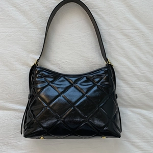 Détail du sac en similicuir matelassé noir avec finition brillante et boucle dorée