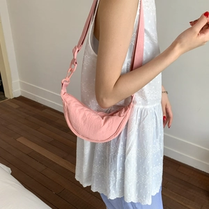 Detailed view of pink crescent nylon bag showing soft texture and adjustable strap