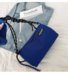 Detail of navy blue mesh crossbody bag with stylish black and white woven rope strap