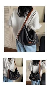 Detail of black nylon crescent hobo bag with silver chain straps and orange label