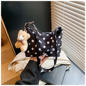 Detail of black and white polka dot shoulder bag with cute plush bear keychain