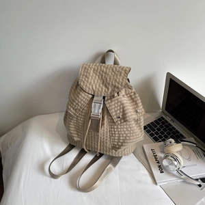 Detailed macro view of beige plaid backpack with white plastic buckle and front pockets