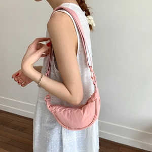 Close-up of pink crescent moon bag showing wrinkled nylon texture and wide shoulder strap