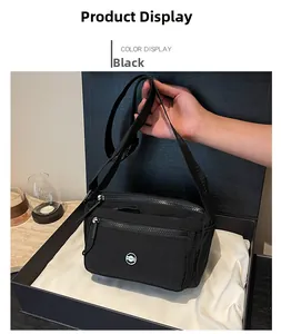Detail of black nylon crossbody bag with multiple zippers and wide shoulder strap
