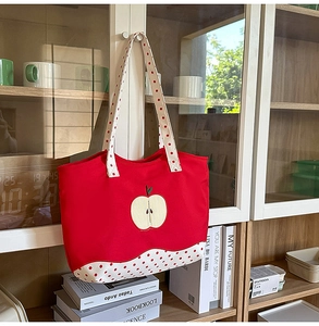 Detail view of red canvas tote bag with apple embroidery hanging on a cabinet