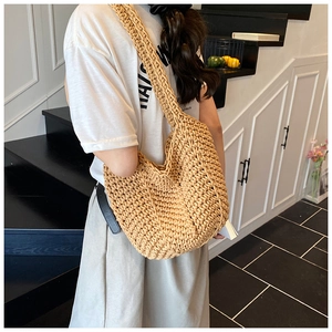 Detailed close-up showing the handmade woven texture of the beige straw shoulder bucket bag