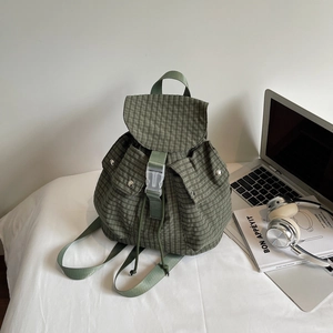 Detail of green plaid backpack featuring drawstring closure and durable buckle strap
