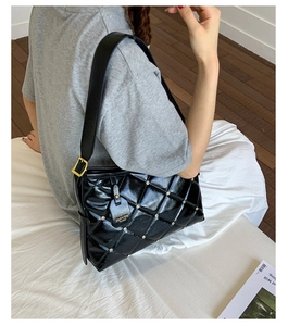 Detail of black quilted shoulder bag featuring crystal studs and gold buckle adjustment