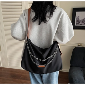 Gros plan du sac hobo en nylon noir avec chaînes argentées et bandoulière en cuir brun