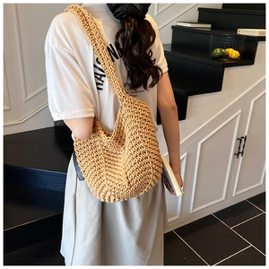 Detail of hand-woven crochet hobo bag in beige rope texture shown on shoulder