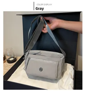 Detailed view of grey nylon crossbody bag with adjustable wide strap and zipper compartments