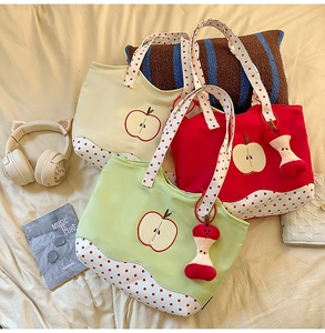 Detailed view of canvas tote bags with apple embroidery and red polka dot pattern handles