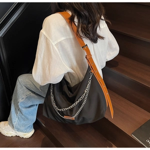Détail du sac cabas en nylon noir avec chaînes argentées et bandoulière en cuir marron