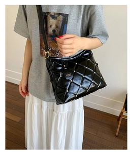 Détail d'un sac bandoulière en cuir matelassé noir avec clous dorés sur mannequin