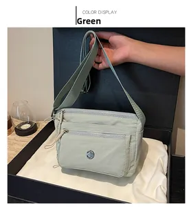 Detail view of light green crossbody bag with multiple zip compartments and wide shoulder strap