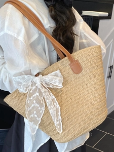 Large woven tote bag with brown leather straps and white lace bow for summer beach travel