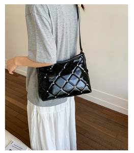 Detail of black quilted shoulder bag featuring gold studs and Fashion hanging tag