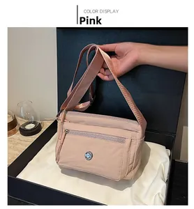 Detail of pink nylon crossbody bag with multi-zipper pockets and brand logo