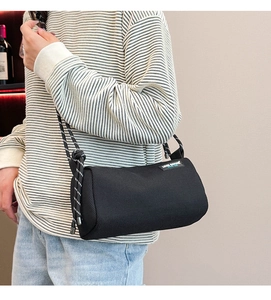 Close-up of black cylindrical canvas crossbody bag with decorative rope strap details