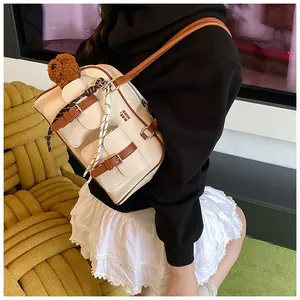 Detailed shot of retro canvas shoulder bag with brown leather trim and plush teddy bear charm
