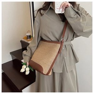 Détails du sac seau en paille tressée avec bordure en cuir marron et bandoulière réglable