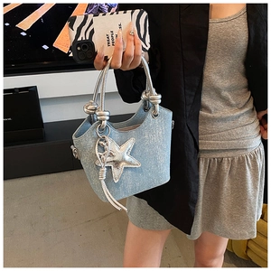 Detail of light blue bucket bag with silver handle and star charm accessory on the side