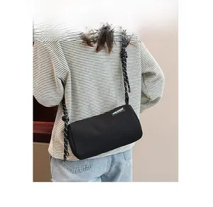 Detail of black cylindrical canvas crossbody bag with decorative woven rope strap