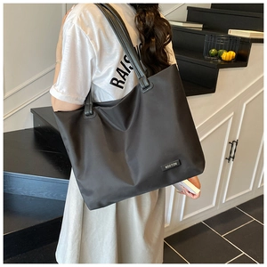 Rear view of a minimalist black large capacity tote bag worn on shoulder for daily commute
