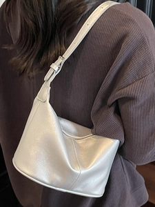 Sac à bandoulière hobo argenté avec bandoulière réglable porté par un mannequin au style épuré