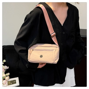 Detail of the pale pink nylon crossbody bag with multi-layer zippers and metal logo