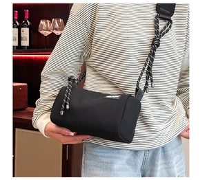 Black mesh cylinder bag with woven rope shoulder strap and branded rectangular label