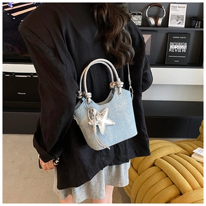 Detail of light blue bucket bag with silver star charm and metallic rope handle