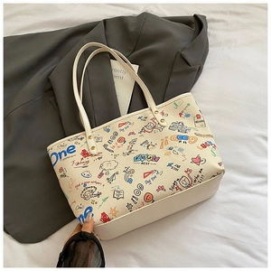 Detail of canvas tote bag featuring colorful graffiti prints and white leather base