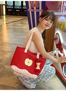 Detail of red canvas tote bag with apple print, polka dot trim and cute apple core charm