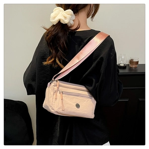 Pink nylon crossbody bag with multi-layer zipper pockets and wide webbing shoulder strap