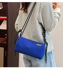 Detail view of blue mesh cylinder crossbody bag with a thick woven rope shoulder strap