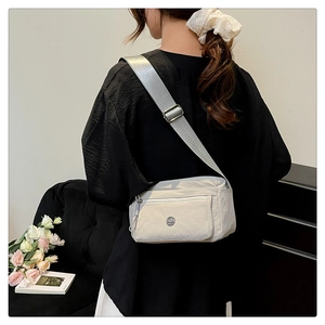 Detail of light grey nylon crossbody bag with water-resistant fabric and metal logo