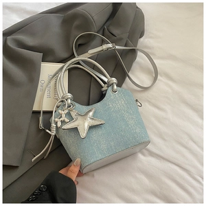 Detailed macro view of light blue bucket bag with silver star charm and metallic handles