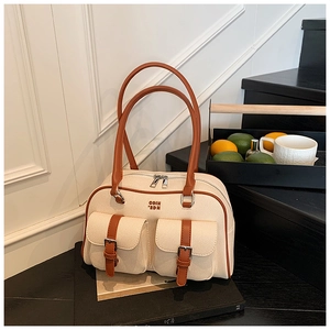 Detail view of cream canvas Boston bag with brown leather handles and buckle pockets